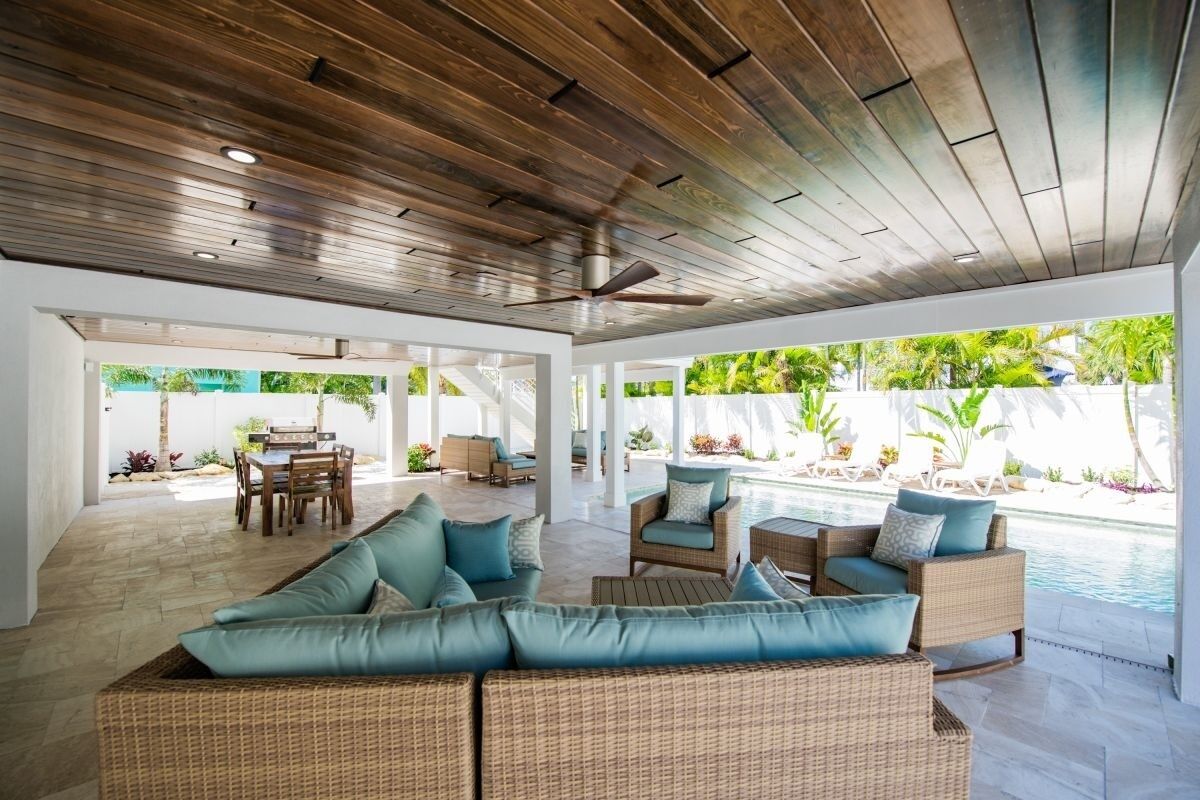 An open-plan living area with a pool, wicker furniture, and a ceiling fan.