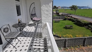 En balkon med en hængestol, et bord med en champagneflaske og et mønstret gulv.