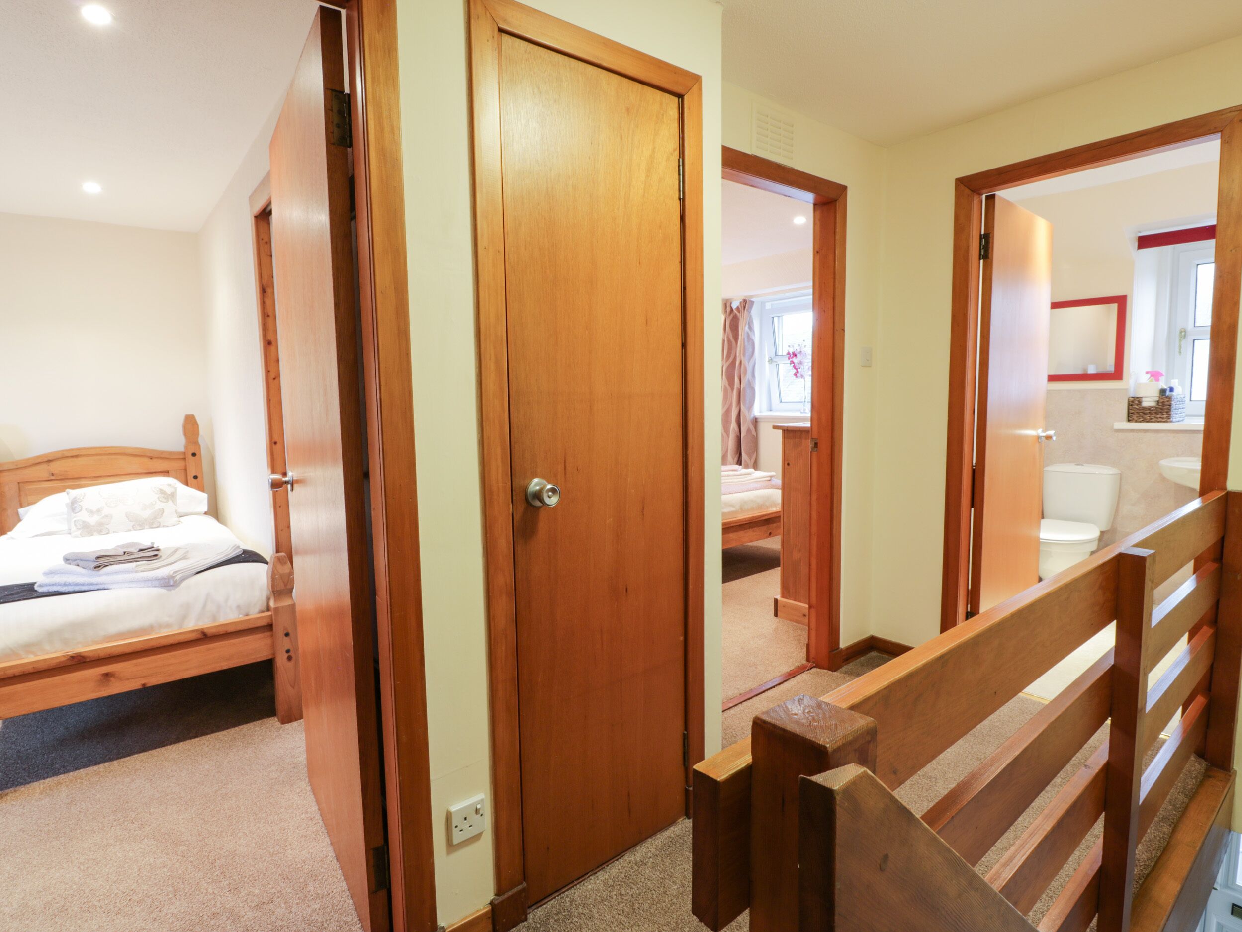 A bedroom with a wooden bed, a wooden door, and a wooden staircase.