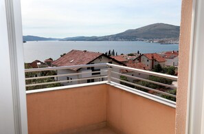 Un balcone con vista su un lago, edifici e una collina.