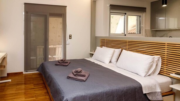 Ein modernes Schlafzimmer mit einem großen Bett, einem Holz-Kopfteil und einer Schiebetür zu einem Balkon.