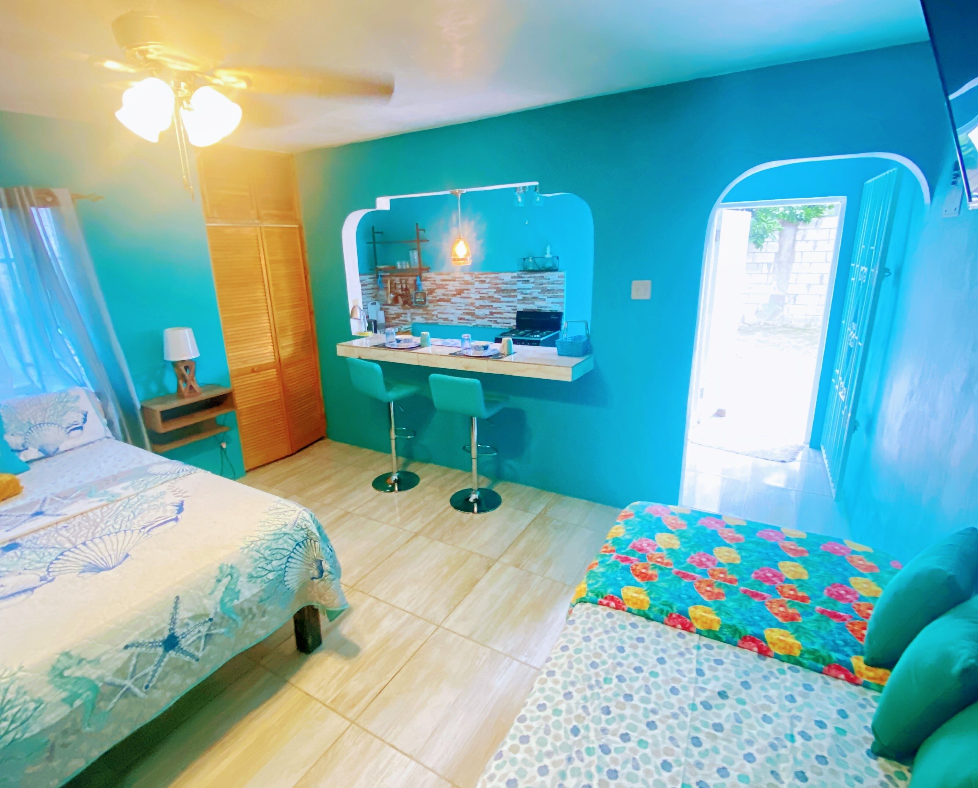 A room with a bed, a desk with a mirror, a chair, and a small table.