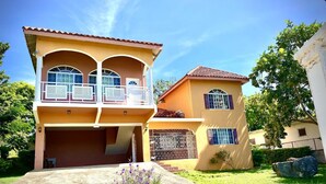 A two-story house with a balcony, a garage, and a small garden area. - YanceyLargo Estate - Newly Built Modern 1 Bedroom Suite 1 Villa by RedAwning (Montego Bay)