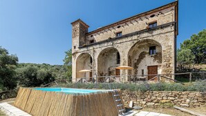 A stone building with arched windows and a swimming pool.