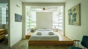 Une chambre à coucher avec un lit, une chaise et un tableau accroché au mur.