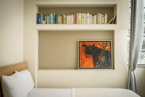 Un dormitorio con cama, estantería y un cuadro enmarcado.