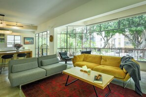 A modern living room with a sofa, a coffee table, and a view of a balcony.