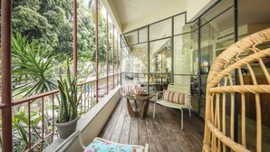 Un balcon avec une table, des chaises et un fauteuil en osier.