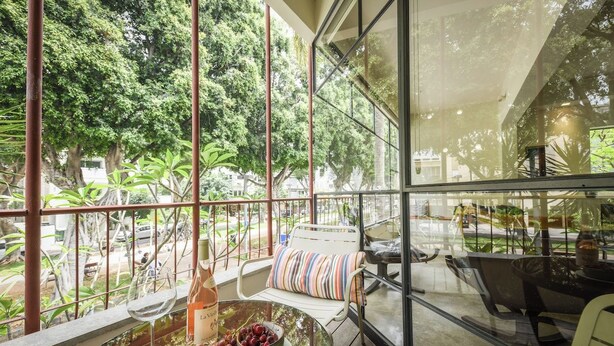 Une pièce avec une table en verre, une bouteille de vin et un bol de raisins.