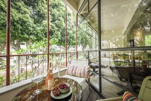 A room with a glass table, a bottle of wine, and a bowl of grapes.