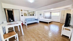 A modern, well-lit room with a sofa, bed, TV, and a small dining area. - My Cretan Village by Go4sea | Studio in Crete (Chorafakia)