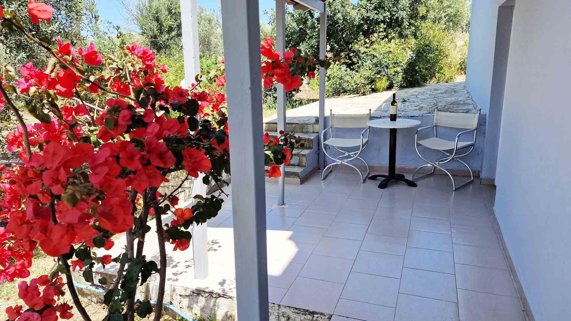 A covered outdoor patio with white tiled flooring, metal-framed chairs, and a table.