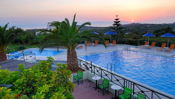 A swimming pool with lounge chairs and umbrellas, surrounded by greenery and palm trees. - My Cretan Village by Go4sea | Studio in Crete (Chorafakia)