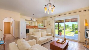 A spacious living room with a sofa set, a wooden coffee table, and a view of the garden through a sliding glass door. - Stunning 5-bed Villa in Gennadi! (Rhodes)