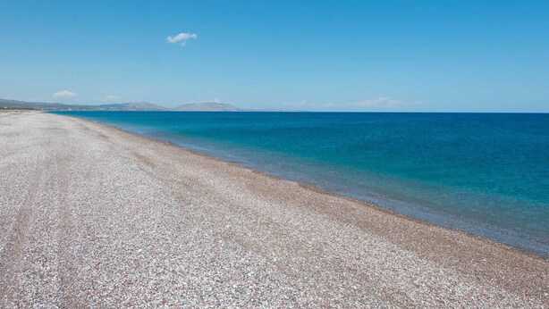 A pebbled beach with clear blue water and distant mountains. - Stunning 5-bed Villa in Gennadi! (Rhodes)