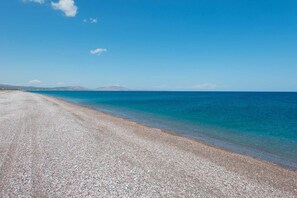 A pebbled beach with clear blue water and distant mountains. - Stunning 5-bed Villa in Gennadi! (Rhodes)