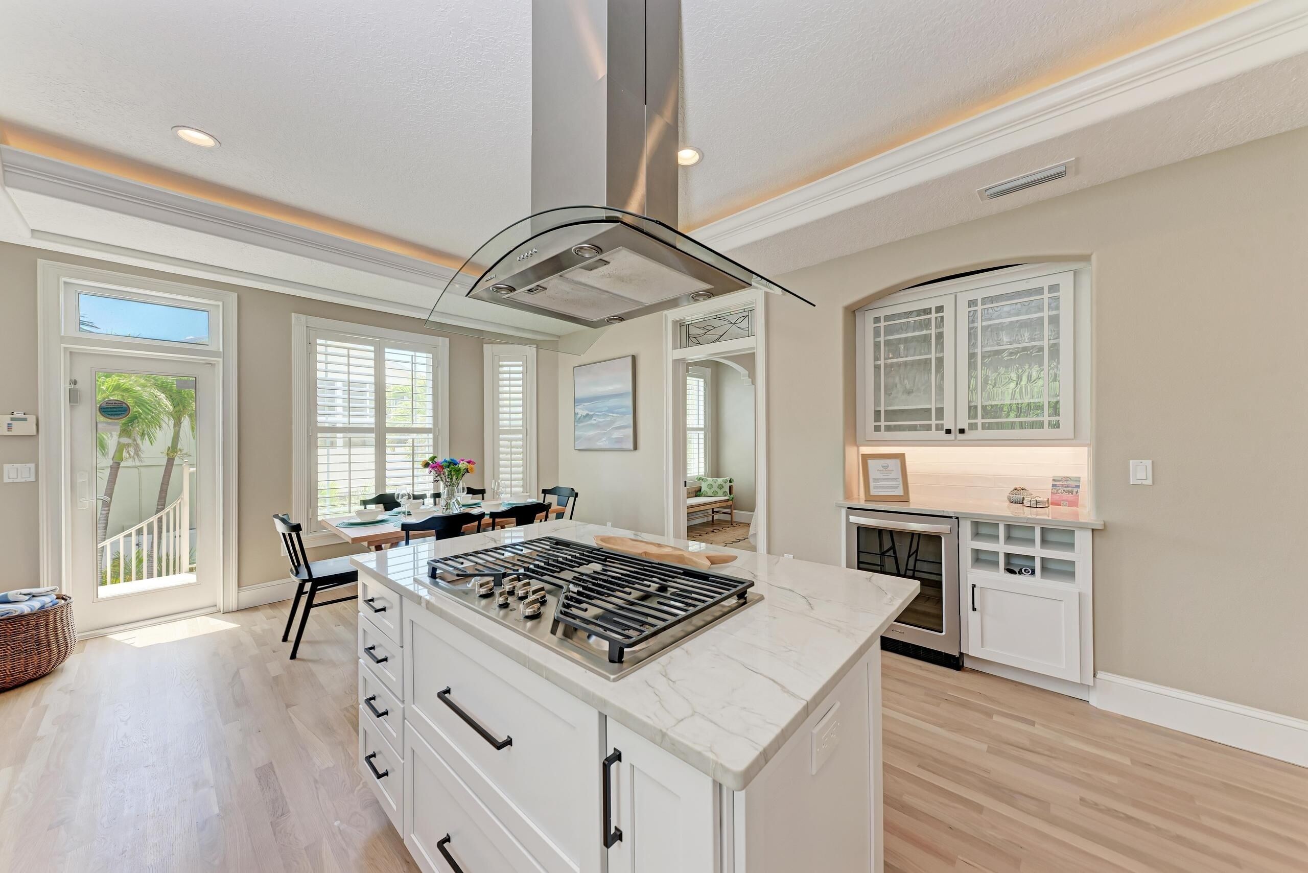 A spacious kitchen with a central island, white cabinetry, and a large window providing natural light.