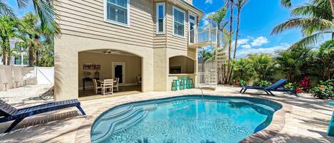 A house with a swimming pool, a covered patio, and a two-story structure.