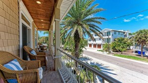 A covered porch with wicker furniture and a palm tree. - Once Upon A Time managed by Beach Retreats (Anna Maria)