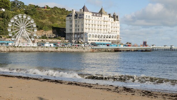 A coastal hotel with a large Ferris wheel and a pier extending into the water. - Ty Arth (Llandudno)