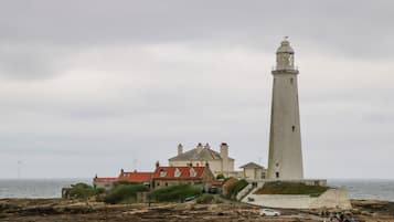 A lighthouse with a tall, narrow tower and a shorter building with a red roof nearby.