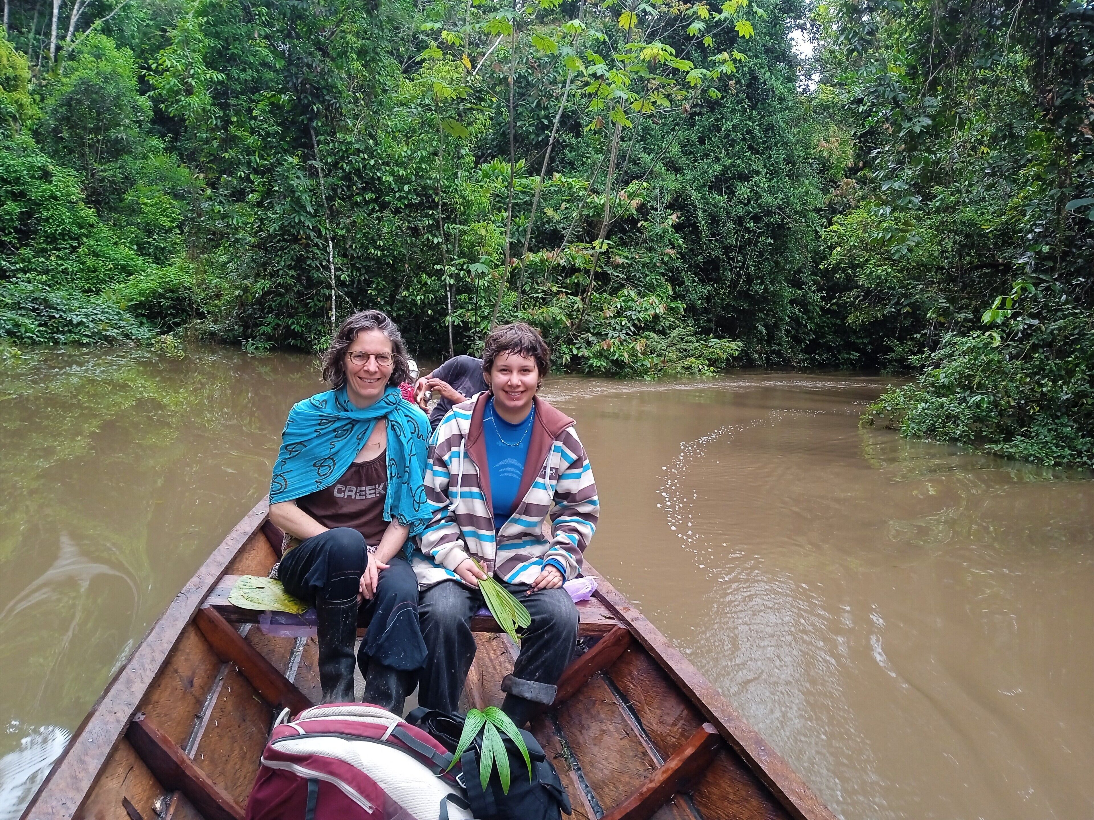 A wooden boat on a river surrounded by dense greenery.