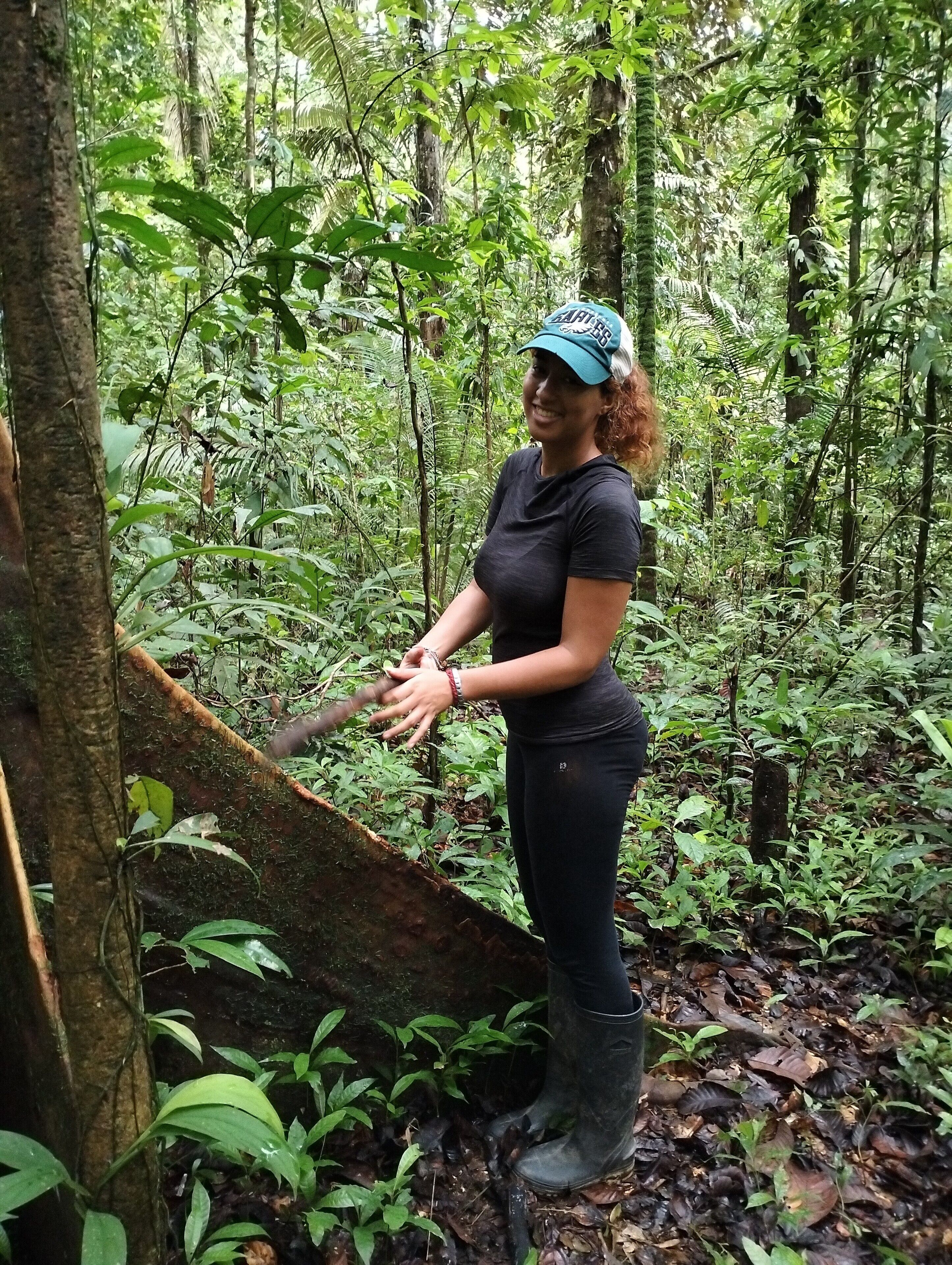 A person standing in a forested area with dense vegetation and trees.