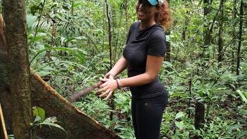 A person standing in a forested area with dense vegetation and trees.