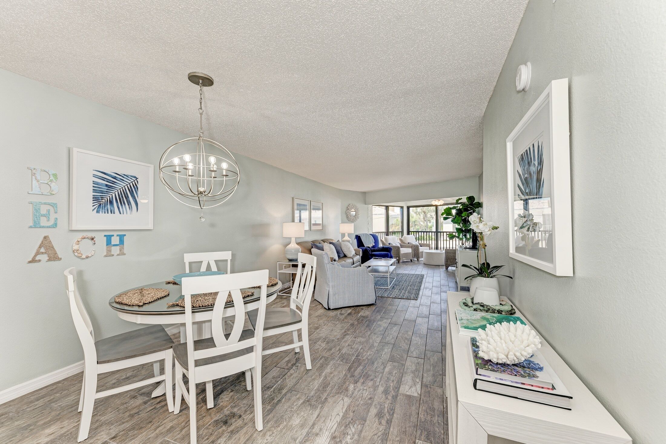 A spacious living area with a dining table, chairs, a sofa, and a chandelier.