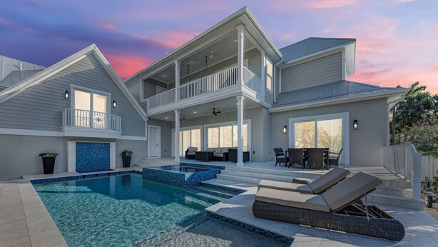 A two-story house with a swimming pool, outdoor seating, and a covered patio. - Just Beachy managed by Beach Retreats (Holmes Beach)