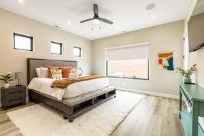 A modern bedroom with a bed, nightstands, a ceiling fan, a window, and a wall-mounted TV. - Sunshine Retreat 2 Bedroom Home by RedAwning (Washington)