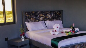 Quarto com uma cama, mesa de cabeceira de madeira, uma banheira grande e uma janela.