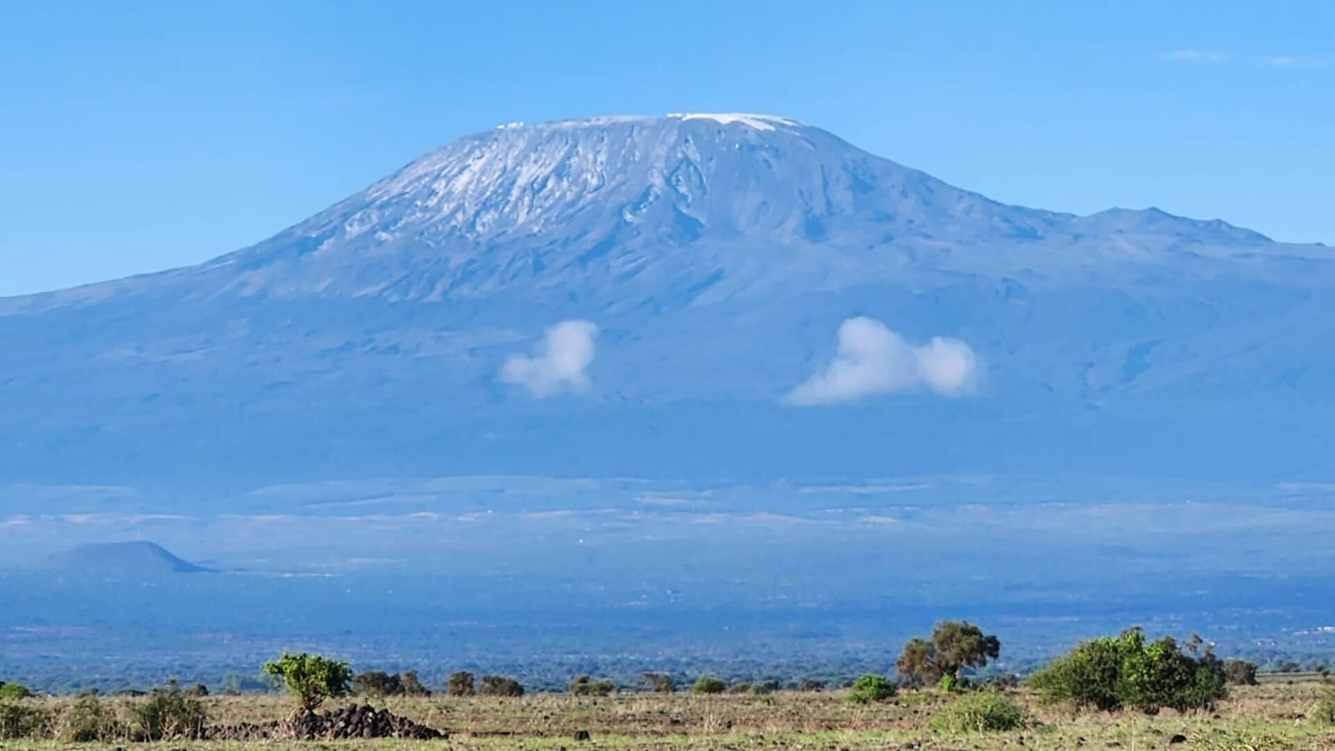 A mountain with a snow-capped peak, a flat-topped summit, and a clear sky.