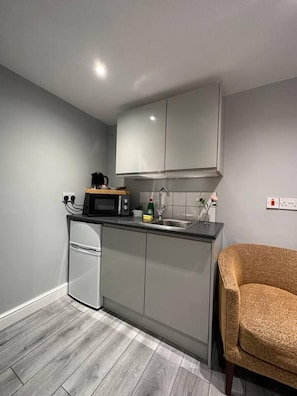A compact kitchen with a microwave, sink, and a small refrigerator. - Luxury Detached Studio Apartment in Luton (Luton)