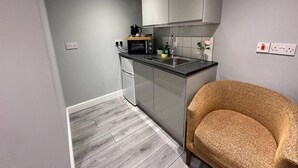 A compact kitchen with a microwave, sink, and cabinets. - Luxury Detached Studio Apartment in Luton (Luton)
