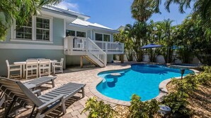 A house with a pool, outdoor furniture, and a staircase leading to a balcony.