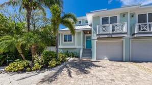A two-story house with a light blue exterior, a blue door, and a garage with two white doors.