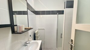 A modern bathroom with a white sink, a glass shower enclosure, and a mirror with a black frame. - La Maison du Bonheur, une Ancienne Maison de Pêcheur Pour 3 Personnes (Le Crotoy)