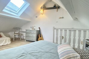 Ein Schlafzimmer mit Oberlicht, einem Bett, einer Gitarre, einem Schminktisch und einem Stuhl.
