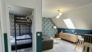 Ett rum i studentkorridorsstil med våningssängar, ett litet kök, en matplats och ett takfönster.