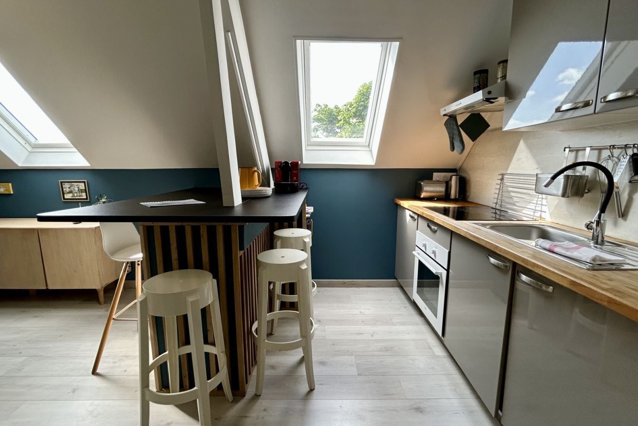 A modern kitchen with a skylight, wooden bar stools, a built-in oven, and a view of the outdoors.