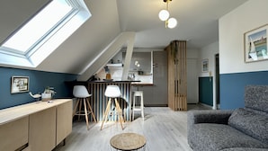 En modern loftlägenhet med kök, matplats och ett stort fönster.