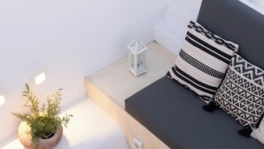 Un'area living moderna con un divano, cuscini, un tavolino, un tavolino in vimini, un tappeto decorato e una pianta in vaso.