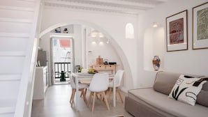Un soggiorno moderno con un divano, un tavolo da pranzo con sedie e una zona cucina visibile attraverso un arco.