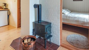 Una stanza accogliente con un camino a legna, un letto con copriletto e un angolo cottura con macchina da caffè.