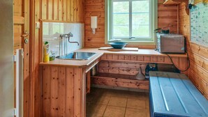 Una cucina compatta con pareti in legno, un lavello, una finestra e un piccolo frigorifero.