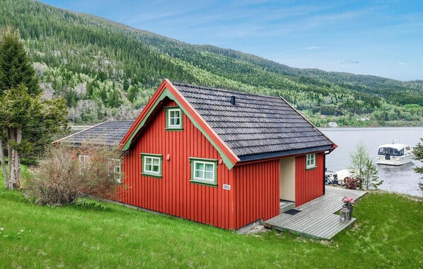 Ein rotes Holzhaus mit geneigtem Dach, einer kleinen Veranda und der Hausnummer 105 an der Vorderseite.