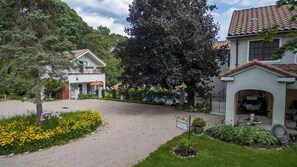 Zona residencial con camino de grava, un letrero que indica un jardín de registro y una variedad de plantas con flores.