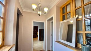 Ein Flur mit einer Chandelieber, Holzfensterrahmen und Fliesenboden.