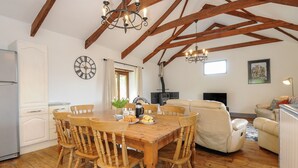 A spacious living area with a wooden dining table, chairs, a sofa, and a fireplace. - Mill House (Lostwithiel)
